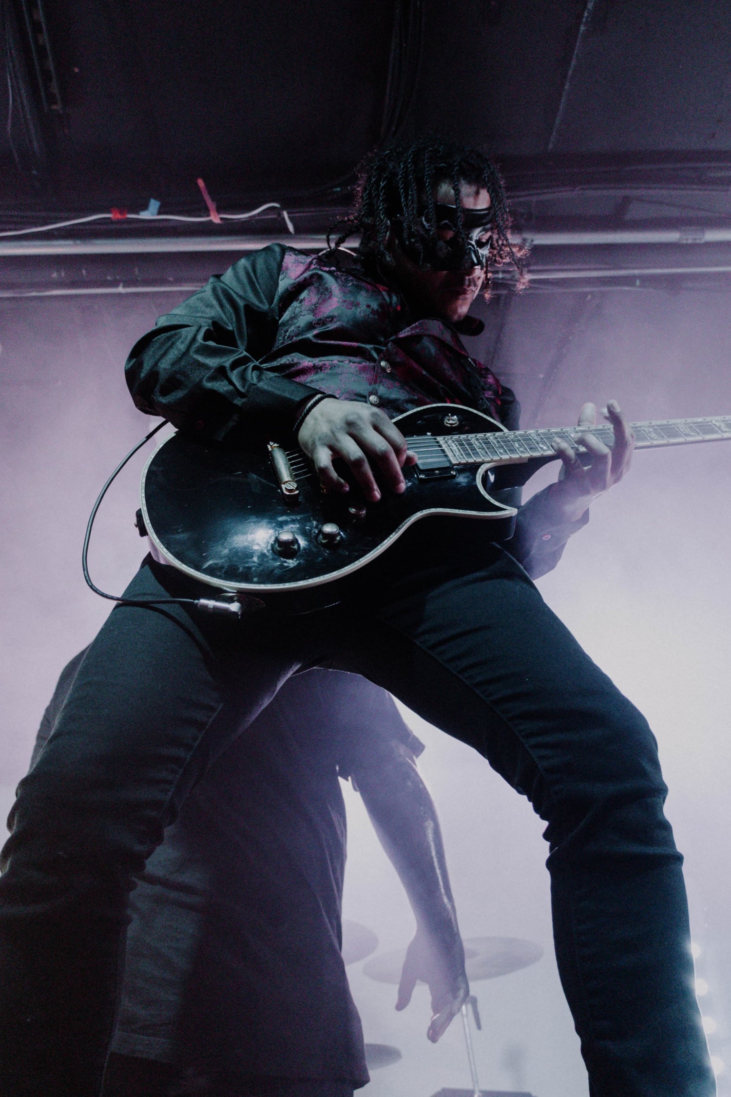 Anthony playing guitar on stage with a dark and moody atmosphere for Stories Through Storms