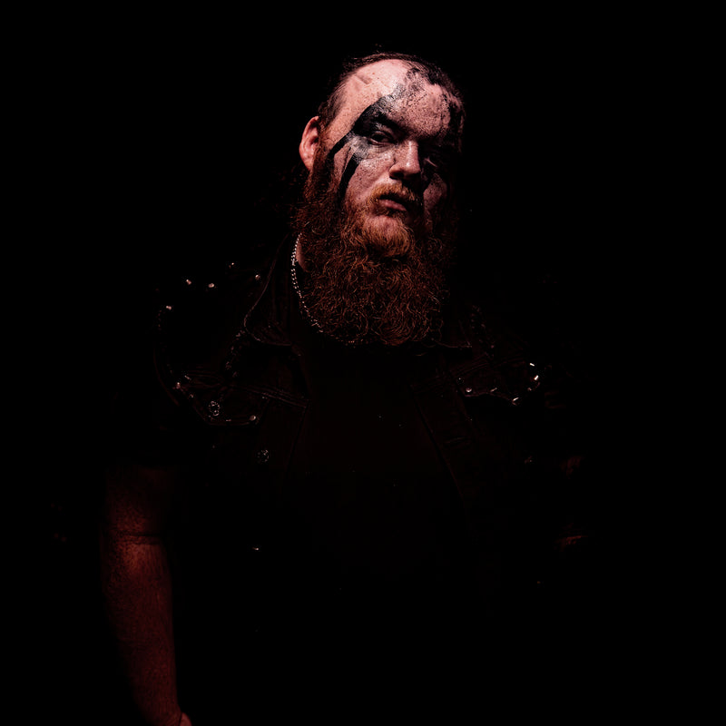 Person with dark hair and beard in a dimly lit setting