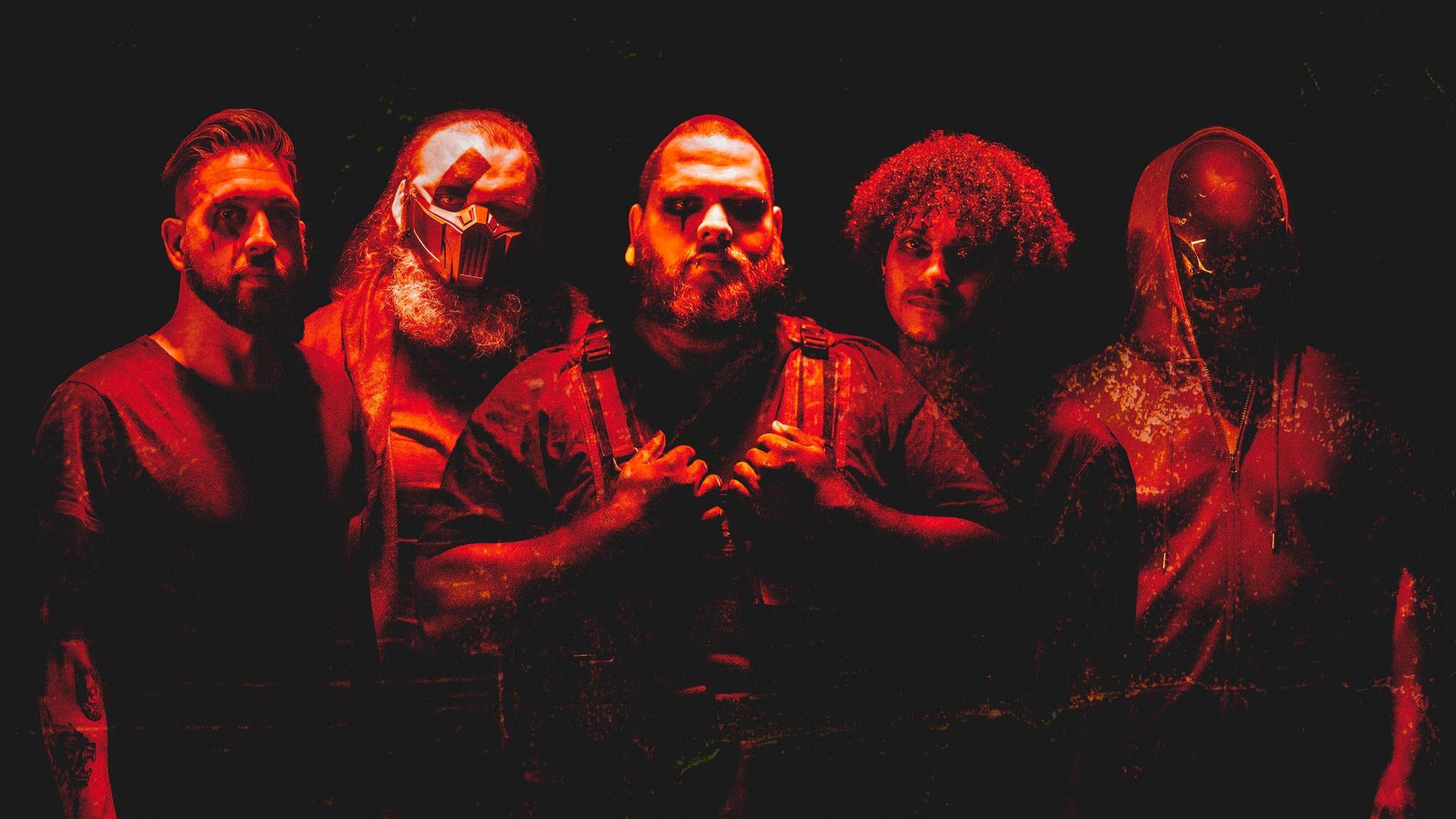 Five people wearing masks in a dark setting with red lighting these are the band members of Stories hrough Storms