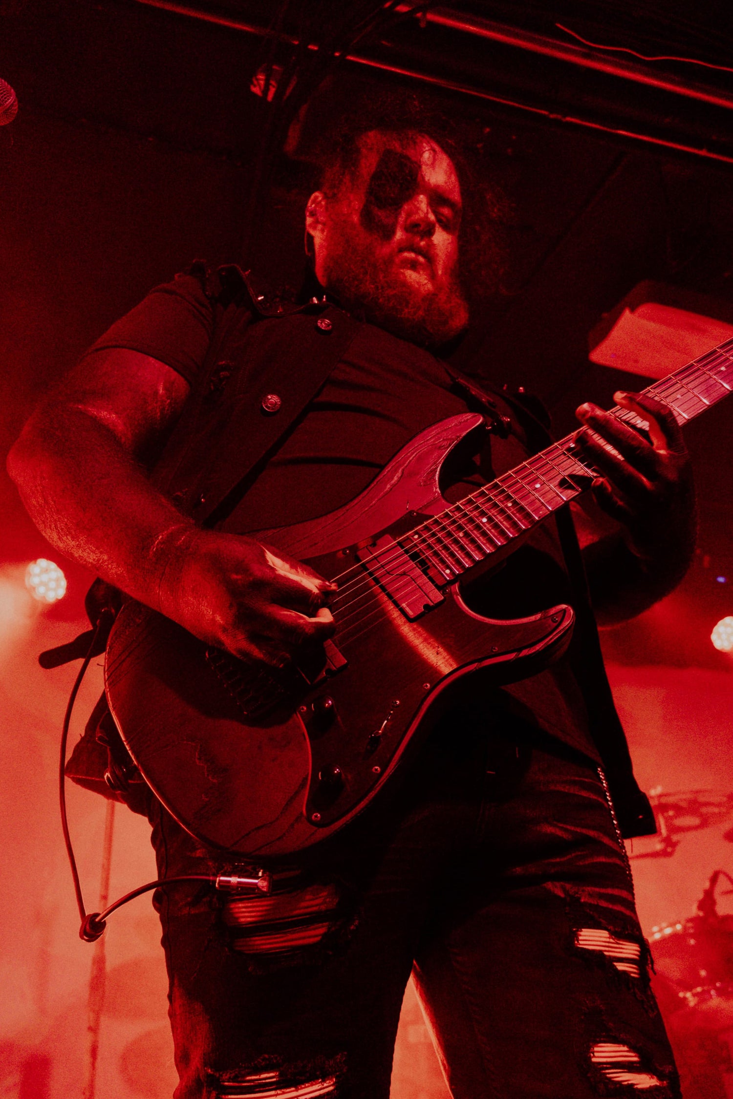 Timmy Taylor playing guitar on stage with red lighting for Stories Through Storms.